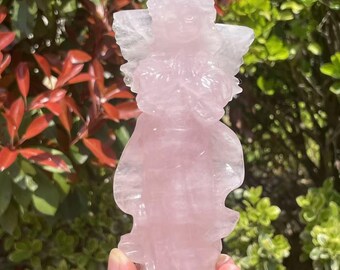 May include: A pink rose quartz angel figurine with wings outstretched. The angel is carved in a standing pose with hands clasped in prayer.