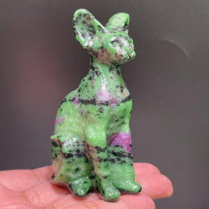 May include: Green, black, and pink carved cat figurine made of green aventurine gemstone.