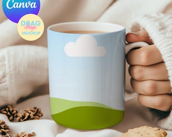 May include: A white ceramic mug with a blue sky, white cloud, and green hills design. The mug is filled with a brown liquid and is being held by a hand.