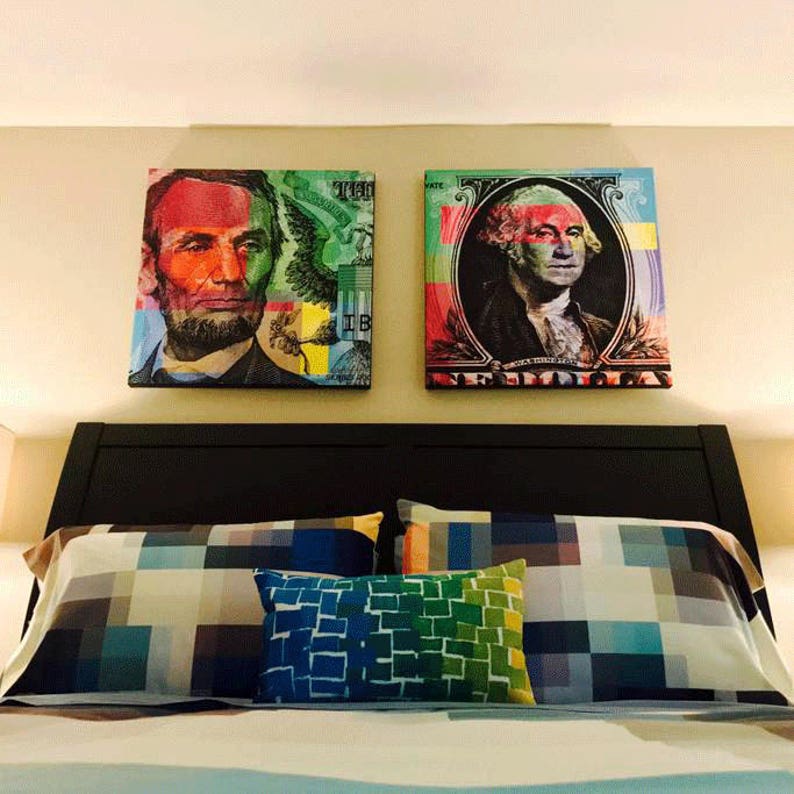 May include: Two framed canvas prints of American presidents, George Washington and Abraham Lincoln, with a colorful, pixelated design. The prints are hanging above a bed with a checkered patterned comforter and pillows.