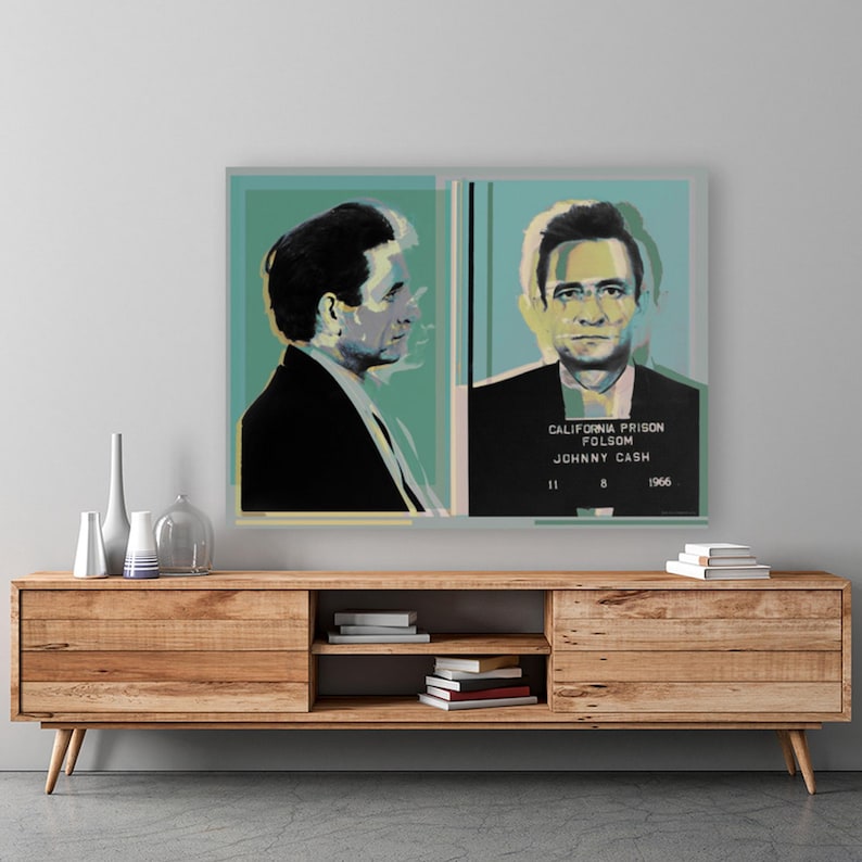 May include: A pop art style portrait of Johnny Cash with a blue, green, and yellow color scheme. The image is a mugshot style photo with text that reads "California Prison Folsom Johnny Cash 11 8 1966".