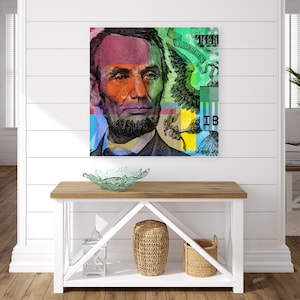 May include: A colorful abstract art print featuring a close-up of Abraham Lincoln's face from a US dollar bill. The image is divided into squares of different colors, including red, green, blue, yellow, and orange. The text "ONE THOUSAND" and "SERIES 2009" are visible in the image.