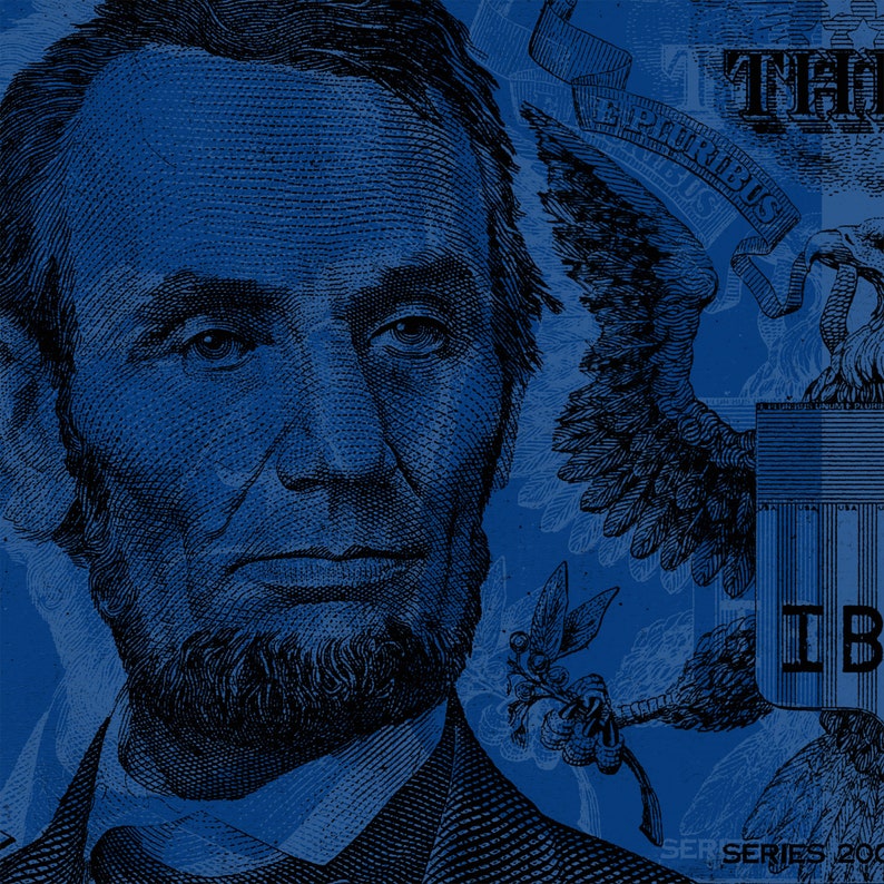 May include: A close-up of a blue and white US dollar bill featuring a portrait of Abraham Lincoln. The bill also features the words "The United States of America" and "One Dollar" in blue lettering. The bill is in focus, while the background is blurred.