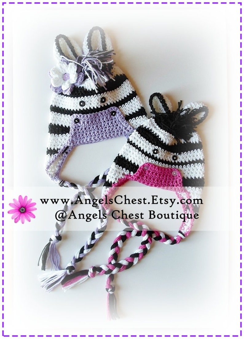 May include: Two crocheted zebra hats with black and white stripes, one with a purple flower and the other with a pink flower. The hats have black eyes and a black nose. The hats are tied together with a braided cord.