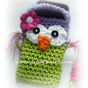 May include: A green, purple, and white crocheted owl phone case with a pink flower on top. The case has black button eyes and an orange beak. The text "@www.AngelsChest.Etsy.com" is visible on the case.