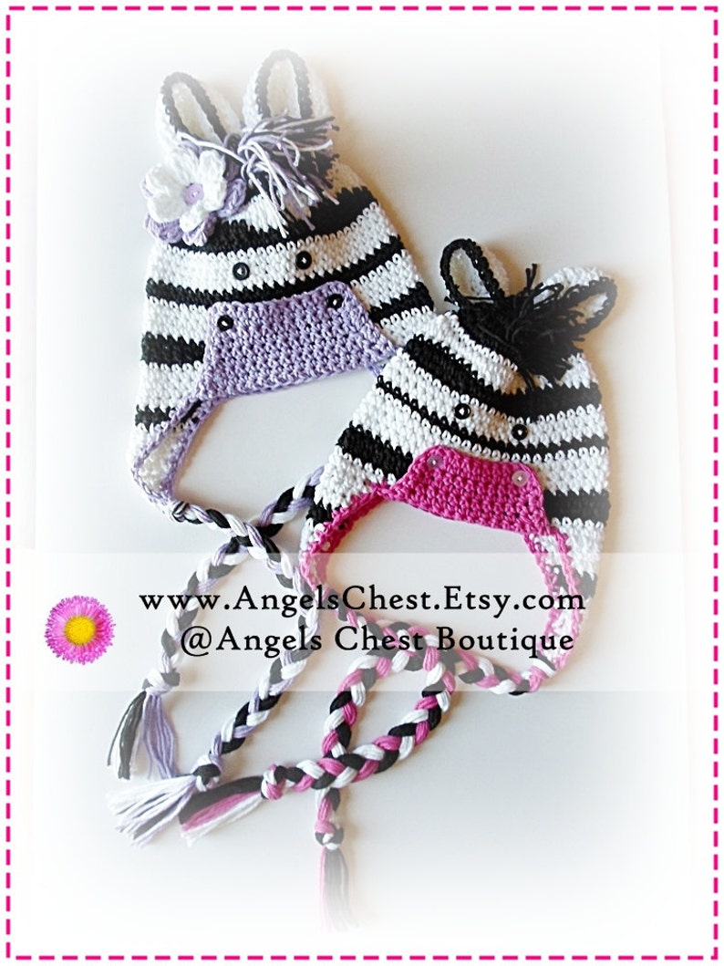May include: Two crocheted zebra hats with black and white stripes, one with a purple lining and the other with a pink lining. Both hats have black ears and a black mane. The hats are tied together with long black, white, and pink braided cords. The text "www.AngelsChest.Etsy.com @Angels Chest Boutique" is visible in the image.