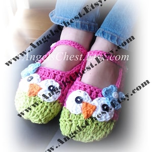 May include: A pair of crocheted owl slippers with pink, green, white, orange, and blue accents. The slippers have a flower detail on the top and a button eye detail.