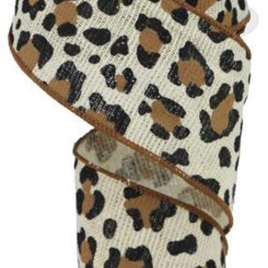 May include: A roll of decorative ribbon featuring a leopard print design. The ribbon has a natural, beige background with brown and black spots. The edges are trimmed with a dark brown border. This ribbon is suitable for crafts, gift wrapping, and various decorative projects.