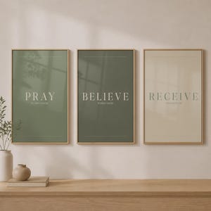 Peut inclure: Trois cadres muraux avec des bordures en bois clair. La première affiche est vert sauge avec le texte PRAY WITHOUT CEASING. La deuxième est vert olive avec le texte BELIEVE WITHOUT DOUBT. La troisième est beige avec le texte RECEIVE WITH GRATITUDE.