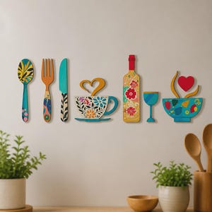 Peut inclure: Un ensemble de décorations murales de cuisine comprenant une cuillère, une fourchette, un couteau, une tasse à café avec de la vapeur en forme de cœur, une bouteille de vin, un verre à vin et un bol avec un cœur. Motifs floraux bleus, rouges et jaunes.