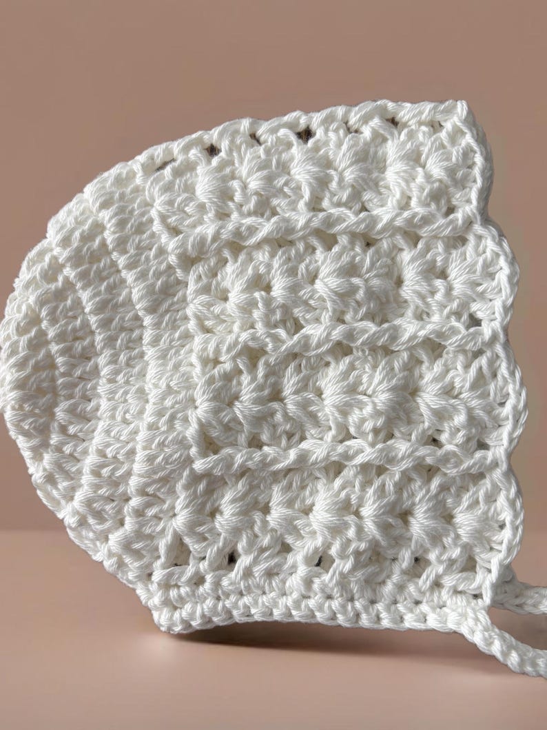 May include: White crocheted baby bonnet with a scalloped edge and ties.