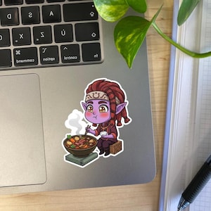 May include: A die-cut sticker featuring a cartoon character with purple skin, pointed ears, and reddish-brown dreadlocks. The character sits on a wooden crate, holding chopsticks and eating from a steaming bowl of stew with vegetables and meat.