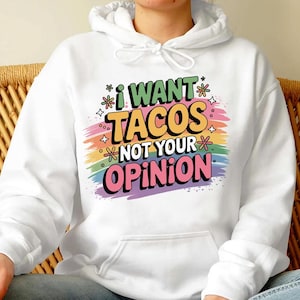 May include: White hooded sweatshirt with the text "I WANT TACOS NOT YOUR OPINION" in colorful, playful lettering. The design includes a rainbow-colored background and decorative stars and flowers.