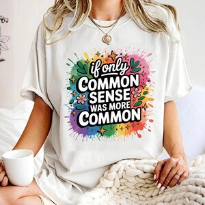 May include: Cream-colored t-shirt with the text "if only COMMON SENSE WAS MORE COMMON" in a colorful, splash-like design. The design includes stars, flowers, and leaves in a rainbow of colors.