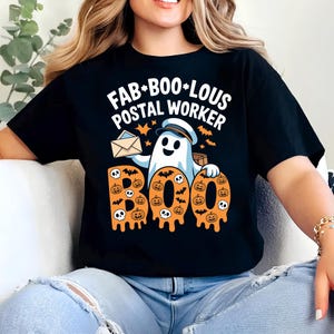 May include: Black t-shirt with the text "FAB*BOO*LOUS POSTAL WORKER" and a ghost graphic holding mail and a package. The word "BOO" is designed with orange pumpkins and skulls.