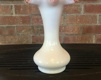 May include: White glass vase with a ruffled pink and gold rim. The vase has a bulbous base and a slender neck, perfect for displaying flowers. The vase is a decorative item.
