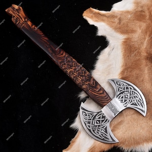 May include: A double-bladed axe with a wooden handle and a silver-colored head. The handle is dark brown with intricate wood grain and carved details. The axe head features a Celtic knot design.