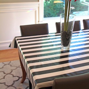 Puede incluir: Un mantel a rayas blancas y negras cubre una mesa de comedor con cuatro sillas. Un jarr&oacute;n con flores rojas se encuentra en el centro de la mesa.