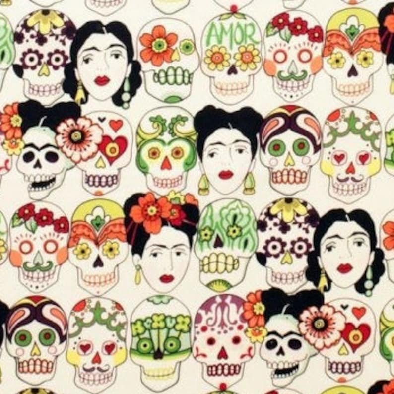 Op de afbeelding: Een witte stof met een herhalend patroon van kleurrijke suiker schedels en gestileerde portretten van Frida Kahlo. De schedels zijn versierd met bloemen, harten en andere ontwerpen. De tekst "AMOR" verschijnt op sommige van de schedels.