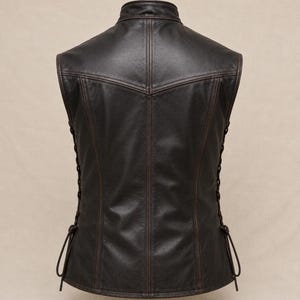 May include: A dark brown leather vest with a stand-up collar and decorative stitching. The vest features lace-up detailing on the sides and a tailored fit. The back view highlights the vest's design and construction.