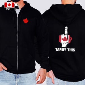 Op de afbeelding: Zwarte hoodie met ritssluiting en een rood esdoornblad op de voorkant. De achterkant heeft een afbeelding van een hand met de Canadese vlag die de middelvinger opsteekt, met de tekst "TARIFF THIS" in het wit.