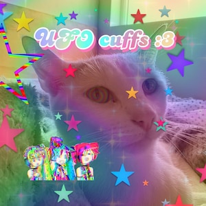 Puede incluir: Un gato blanco con ojos azules y nariz rosa está acostado en una cama con un patrón de estrellas arcoíris. El gato está mirando hacia la derecha. El texto "UFO cuffs :3" está escrito en letras arcoíris en la imagen.