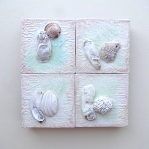 May include: Four square, textured art pieces with a light green and white background. Each piece features a collection of seashells in various shapes and sizes, creating a coastal theme. The seashells are in shades of white and beige.