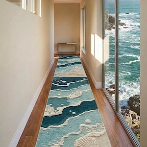 May include: A long, rectangular rug with a beach-themed design. The rug features a blue and white wave pattern, with a seashell, starfish, and spiral design. The rug is placed in a hallway with a wooden floor.