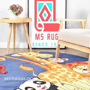 May include: Blue, round children's rug featuring a giraffe, panda, and lion cartoon design. The rug has the text "MSRAGSLOOM" along the edge. A framed poster with a red and turquoise rug design is in the background.