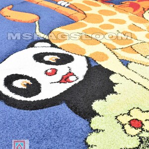 May include: A blue, round rug featuring a giraffe and panda bear design. The giraffe is orange and yellow with brown spots. The panda has black and white fur with red accents. The rug has the text "MS RUGS LOOM".