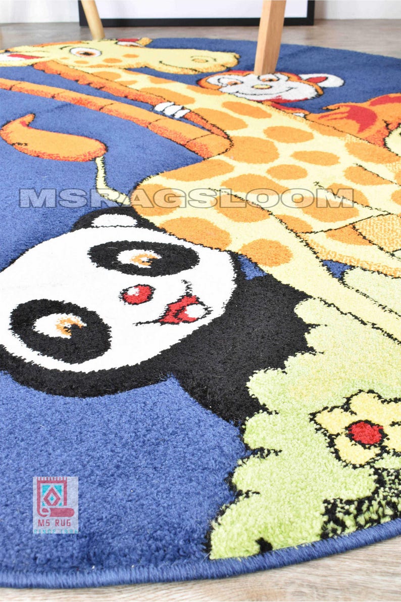 May include: A blue, round rug featuring a giraffe and panda bear design. The giraffe is orange and yellow with brown spots. The panda has black and white fur with red accents. The rug has the text "MS RUGS LOOM".