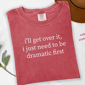 May include: Crimson red t-shirt with white text that reads "i'll get over it, i just need to be dramatic first".