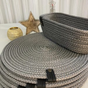Peut inclure: Un ensemble de sets de table ronds tressés argentés et un panier rectangulaire tressé argenté assorti. Chaque article présente une finition métallique et une petite étiquette en similicuir marron foncé avec un rivet métallique sur le côté.