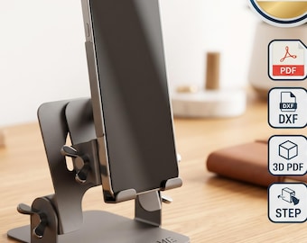 May include: A gray metal adjustable smartphone stand with a flat base featuring the embossed text YOUR NAME. The stand includes wing nuts for angle adjustment and holds a smartphone vertically. A digital download badge displays PDF, DXF, 3D PDF, and STEP icons.