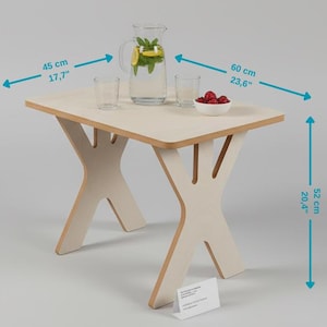 Może przedstawiać: Jasny drewniany stolik boczny z podstawą w kształcie litery X. Stół ma 45 cm szerokości, 60 cm długości i 52 cm wysokości. Szklany dzbanek z plasterkami cytryny i miętą, dwa szklanki i miska malin na wierzchu.