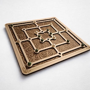 Peut inclure: Un jeu de société en bois de forme carrée. Le plateau présente un motif décoratif tourbillonnant en marron foncé, avec un cadre en bois plus clair. De petits pions verts et blancs sont placés sur le plateau.