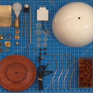 Disassembled view of the handmade bone china table lamp showing the bone china shade, Huali wood base, solid brass fittings, USB module, cord, and lamp components.