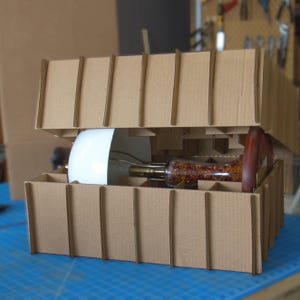 Bone china table lamp packed in a protective cardboard insert, showing the shade, Huali wood base, and lamp body secured for shipping.