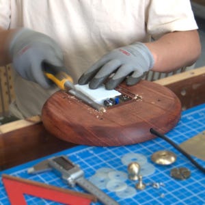 Hand assembly process for the handmade bone china table lamp, showing the Huali wood base, USB module, brass fittings, and tools.