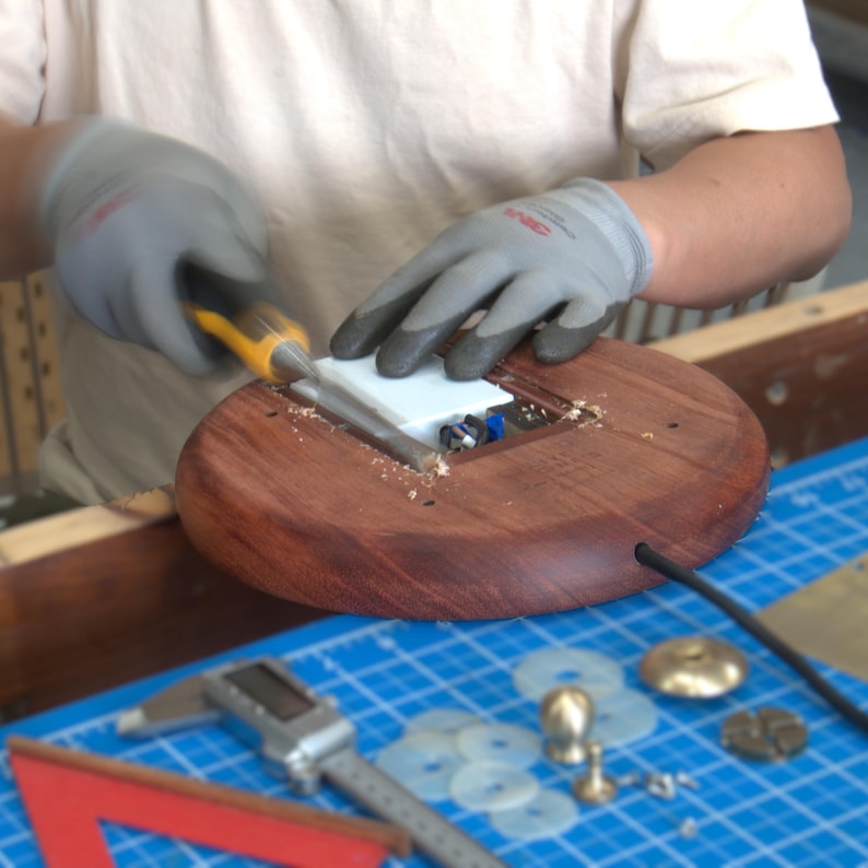 Hand assembly process for the handmade bone china table lamp, showing the Huali wood base, USB module, brass fittings, and tools.