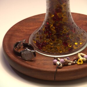 Close-up of the recessed Huali wood tray base holding a watch and jewelry, with the handmade lamp body above.