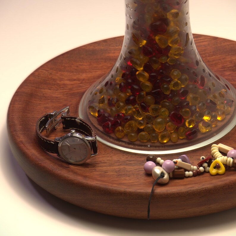 Close-up of the recessed Huali wood tray base holding a watch and jewelry, with the handmade lamp body above.