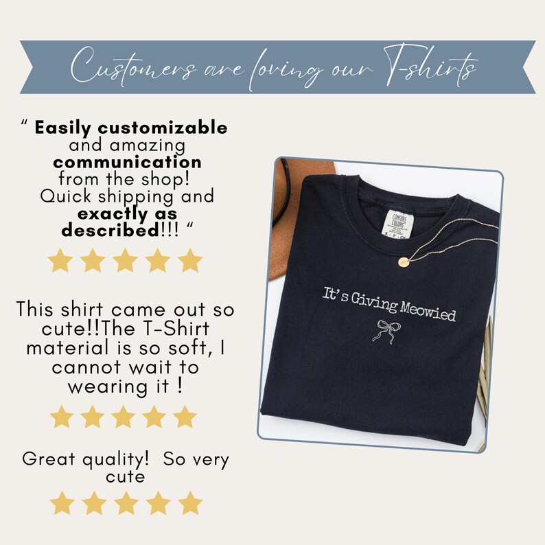 May include: A navy blue t-shirt with the phrase "It's Giving Meowied" embroidered in white. A gold necklace with a pendant is draped on the shirt. The shirt is displayed on a white background.