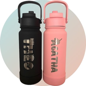 以下が含まれることがあります： 名前入りのステンレス製ウォーターボトル2本。黒いボトルには「Theo」という名前と恐竜のグラフィックが、ピンクのボトルには「Agatha」という名前とユニコーンのグラフィックが描かれています。