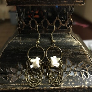 May include: A pair of earrings with a white bone charm and a dangling chain of gold-toned metal.