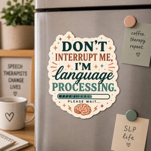 May include: A white and beige magnet with the text "DON'T INTERRUPT ME, I'M language PROCESSING." A brain graphic and a loading bar are also featured. The magnet is on a silver refrigerator.