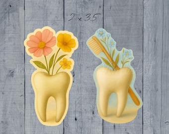 May include: Two whimsical illustrations of teeth. One tooth features peach and yellow flowers, the other a toothbrush and blue flowers. The text "2 x 3.5" is written above the illustrations. The background is a weathered, blue-grey wood.