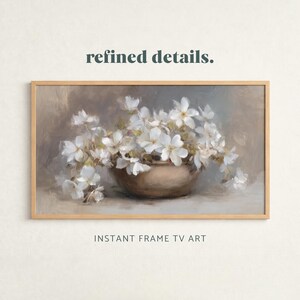 Könnte beinhalten: Ein gerahmtes Kunstwerk mit einem Stillleben weißer Blumen in einer bronzefarbenen Schale. Das Gemälde hat eine weiche, gedämpfte Farbpalette mit dem Text "refined details." und "INSTANT FRAME TV ART".