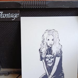 May include: Illustration of a person with long, curly hair wearing a t-shirt with a skull graphic, seated on a red block. The artwork is displayed in front of a black amplifier with knobs and the text "Series-Microlead VG".