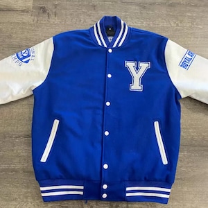 May include: A blue and white varsity jacket with a large white "Y" on the front. The jacket has white sleeves, a striped hem, and the words "Royal Champs" and "Royal Art" on the sleeves.
